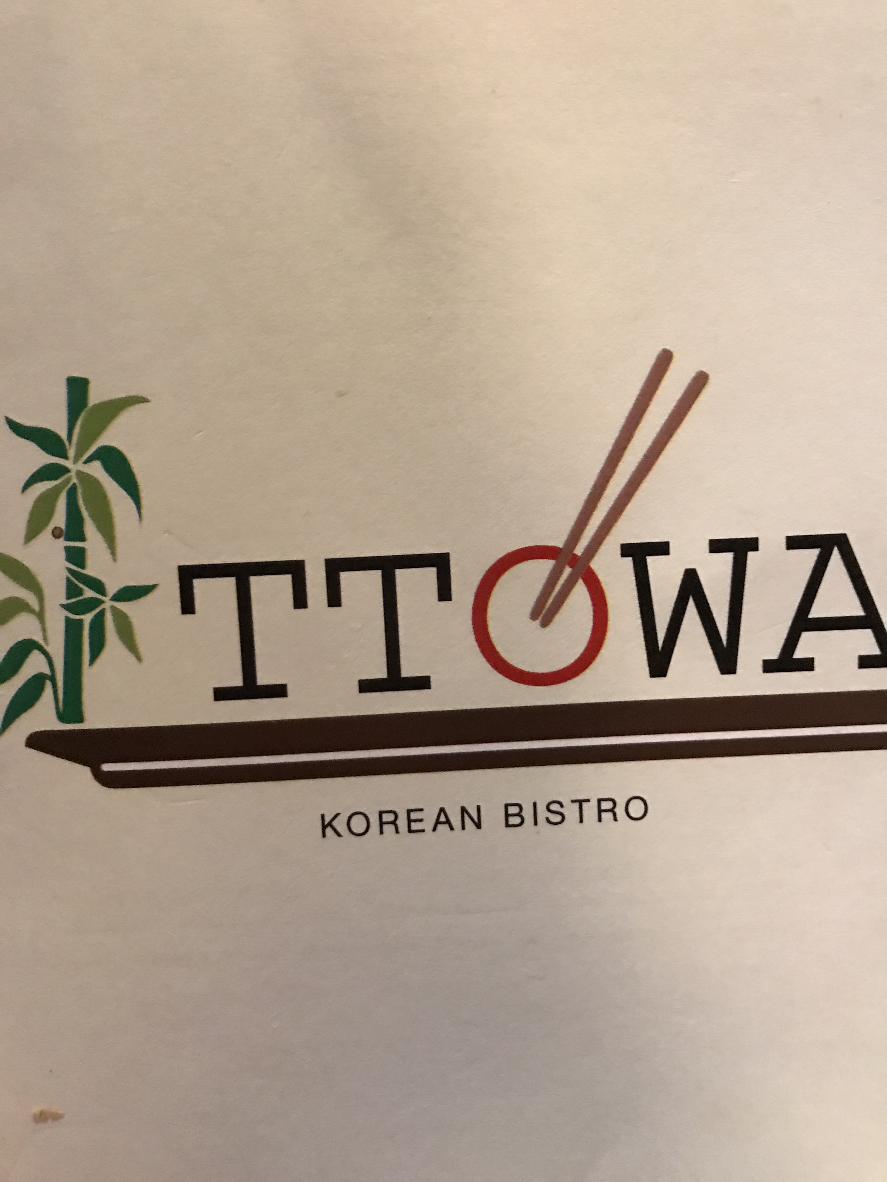 A sign for Ttowa Korean Bistro. There is a drawing of bamboo to the left of the logo and the "o" is a red circle with chopsticks going into it.