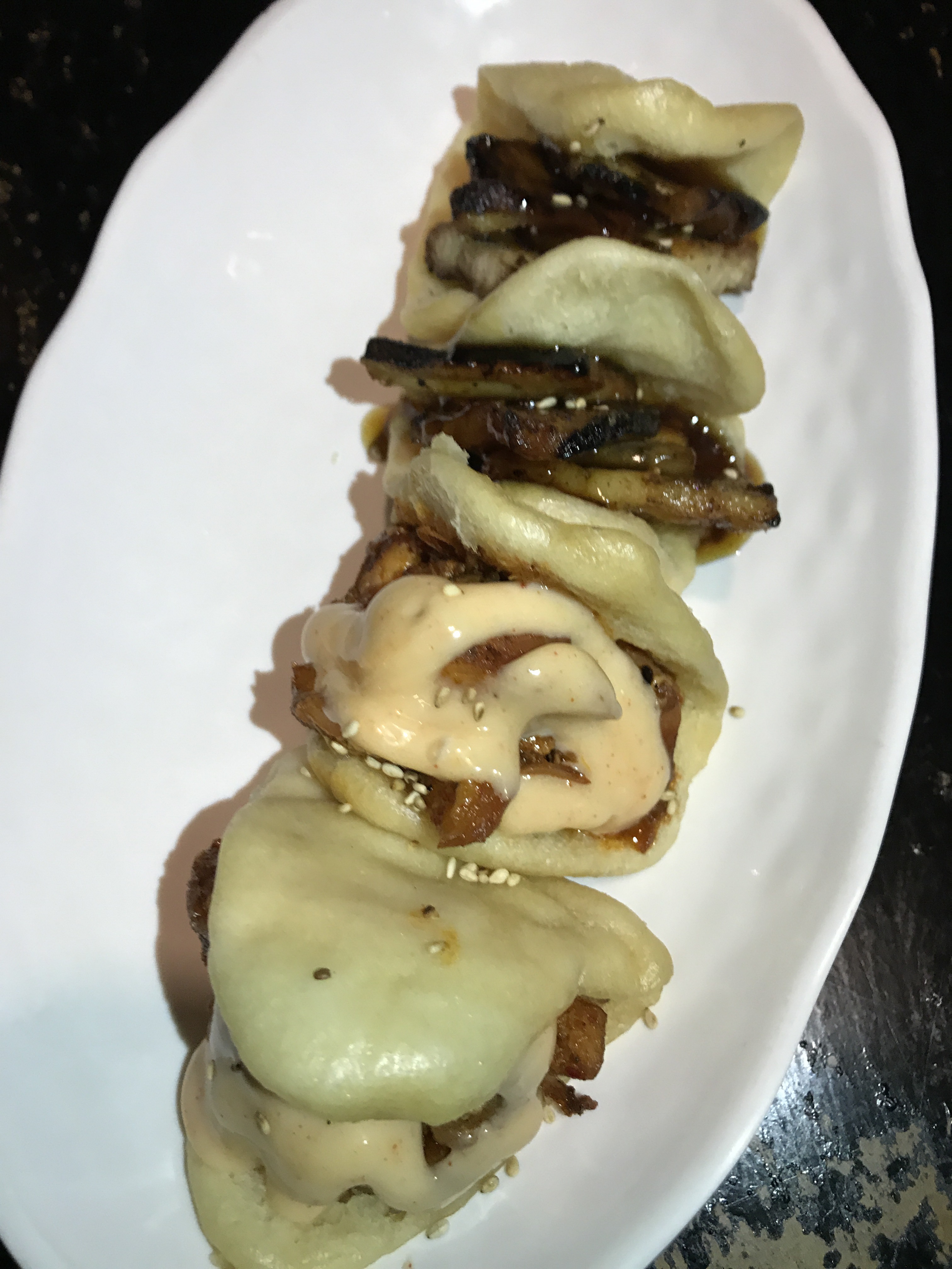 Two pork buns and two chicken buns on a white plate.