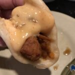 A chicken bun topped with whitish sauce.