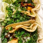 Two tacos covered with cilantro and onion.