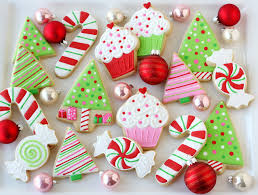 A collection of Christmas cookies, shaped like candy canes, cupcakes, and Christmas trees.