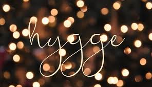 The word "hygge" written in cursive on a background of soft focus lights.