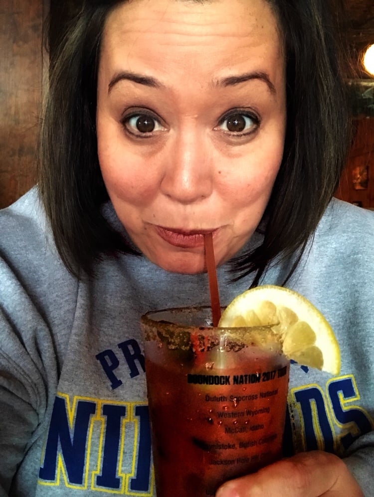 Me drinking a Bloody Mary through a straw. There is a lemon slice on the rim of the glass.