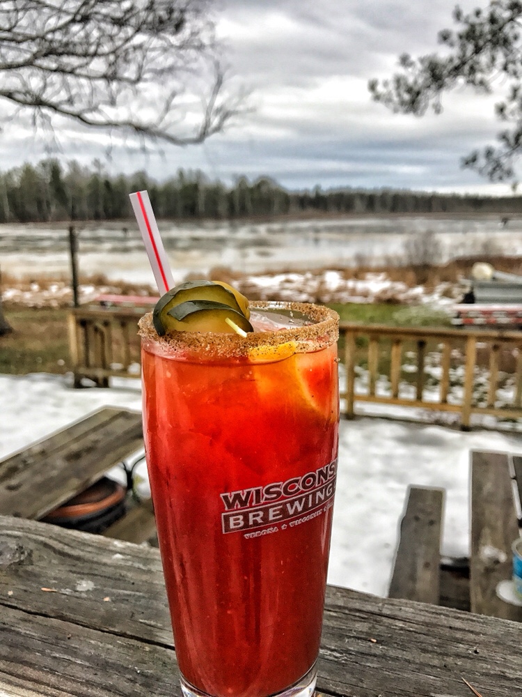 A Bloody Mary topped with pickles overlooking a frozen lake.