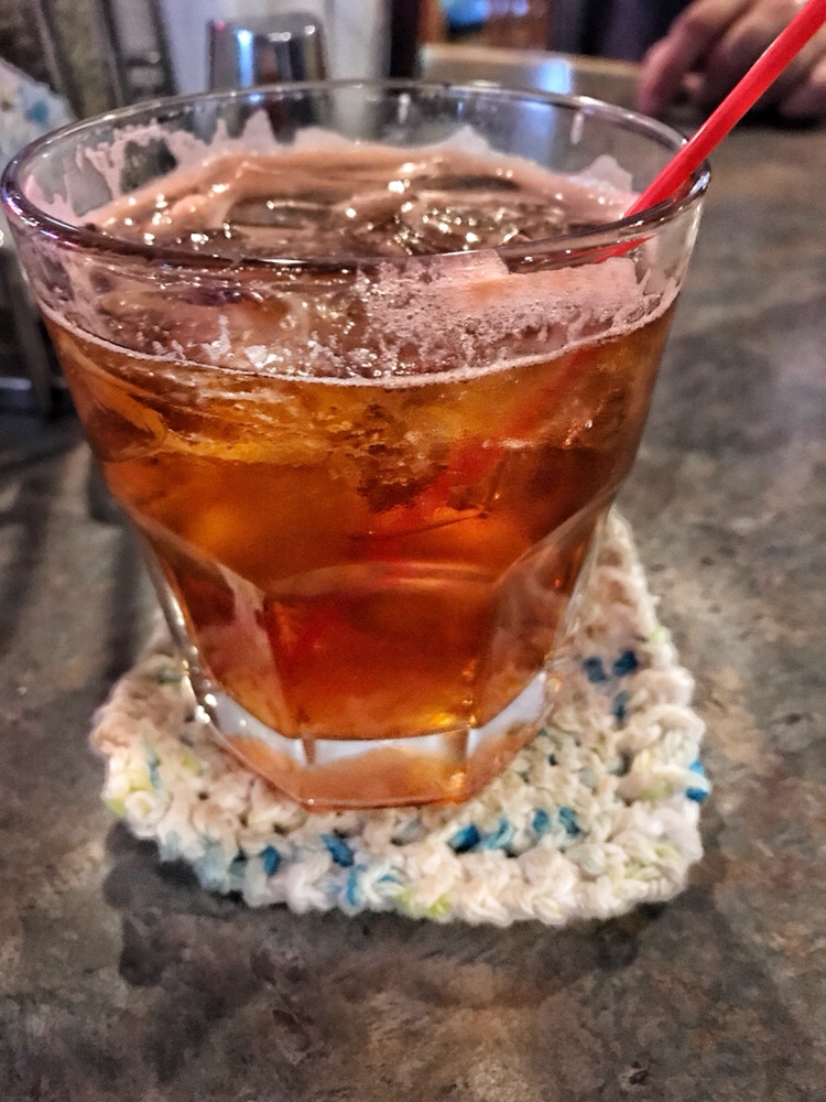 A Brandy Old Fashioned on a knit cozy with a red straw.