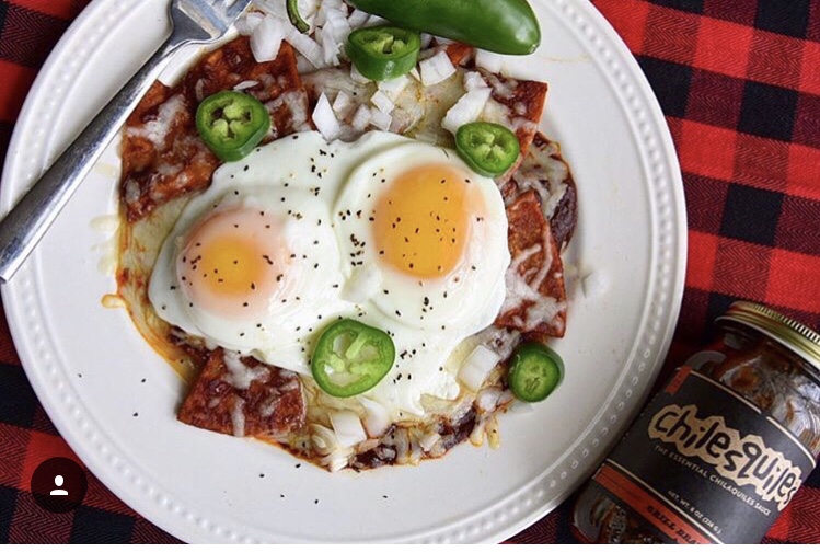 A plate of chilaquiles, tortilla chips topped with cheese, salsa, onions, and jalapenos.