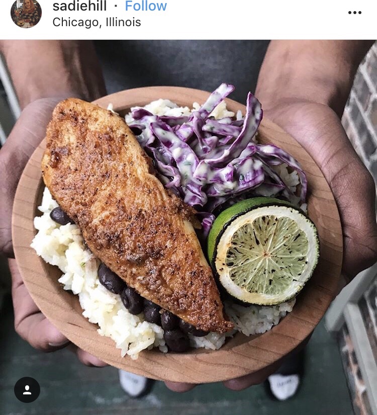 An Instagram post from sadiehill in Chicago, Illinois. It features a wooden bowl with cooked chicken, rice, beans, and a lime slice.