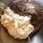 A big dollop of mayo placed on top of chocolate cake mix in a metal bowl.