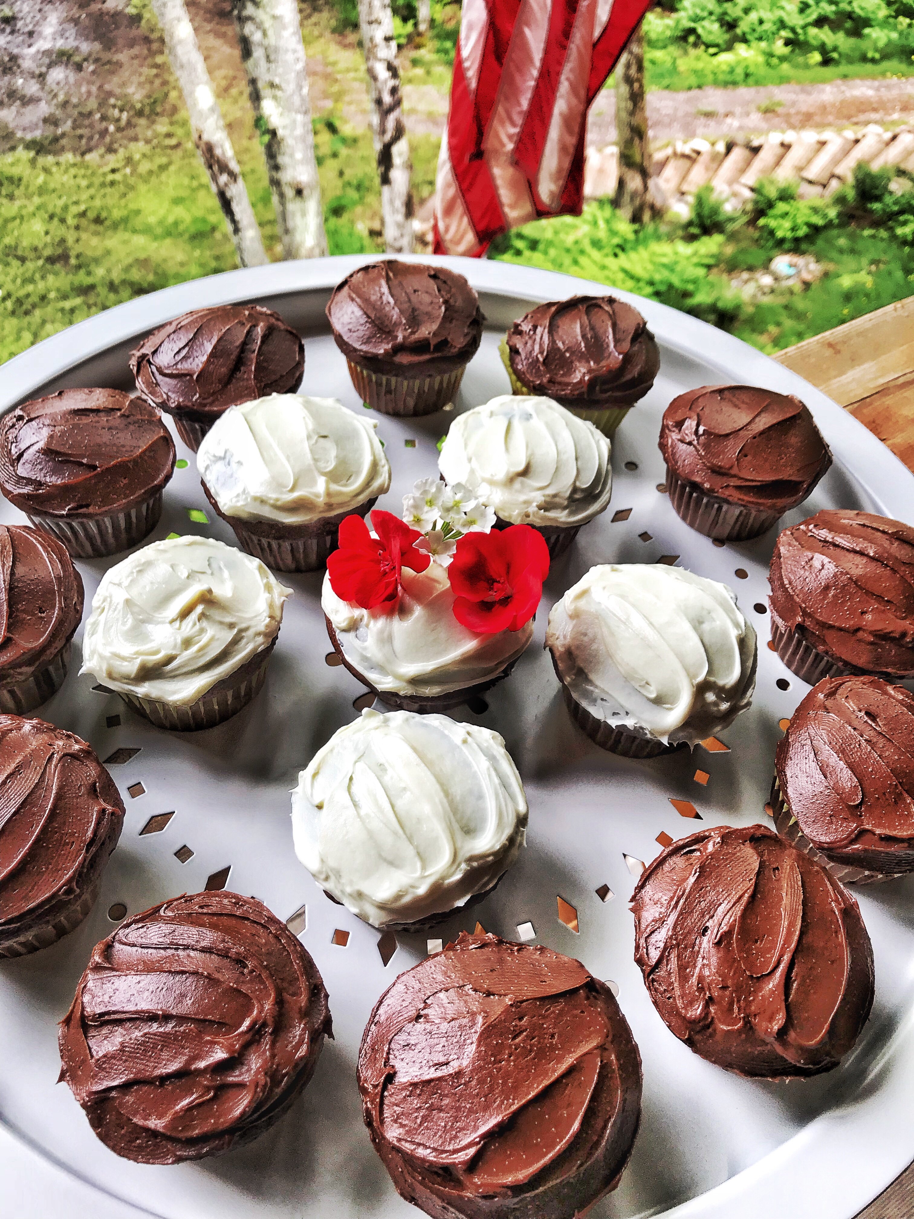 Chocolate cupcakes on a circular platter. The cupcakes on the outer rim are frosted with chocolate frosting while the cupcakes in the center are frosted with vanilla frosting.