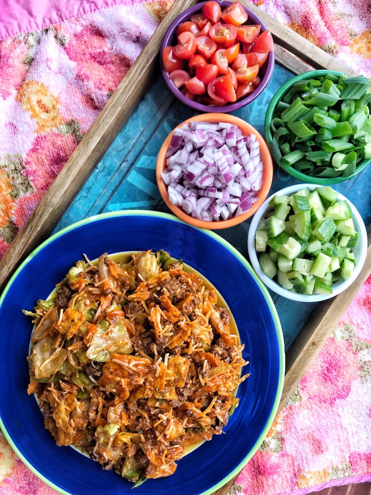 Doritos taco salad alongside diced red onions, cucumbers, green onions, and tomatoes.