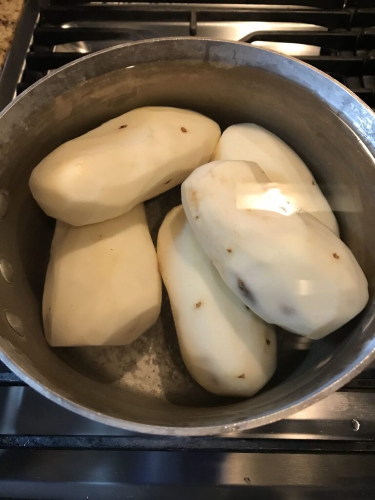 Skinned potatoes soaking in a pot.