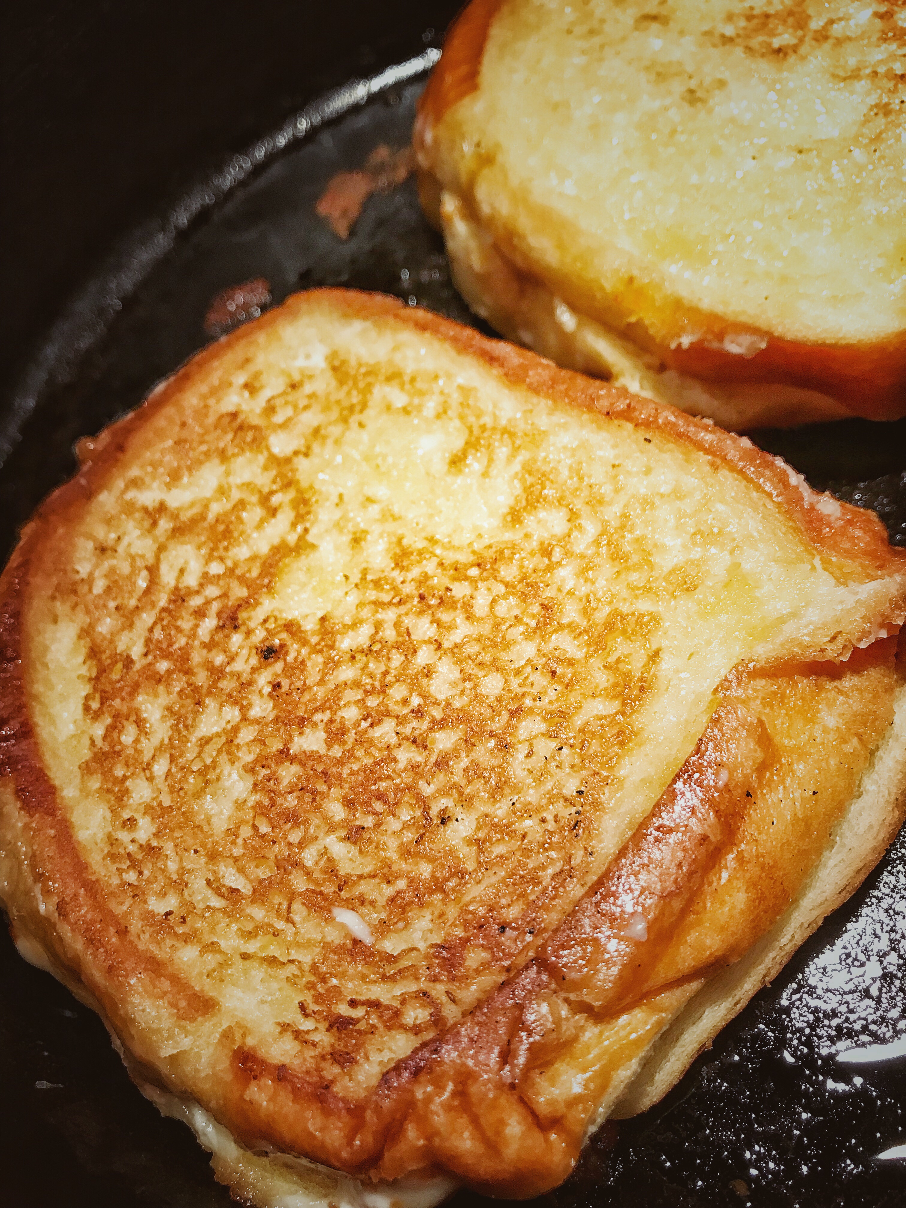 A finished, browned grilled cheese sandwich in a skillet.