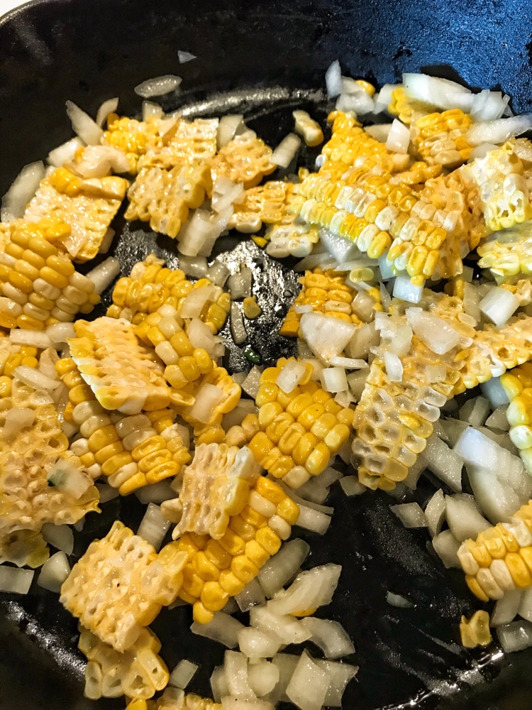 Corn and onions in a skillet.