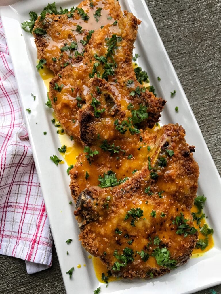 Breaded pork chops with parsley and sauce.