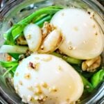 Eggs and green onion covered in the marinade seen from above.