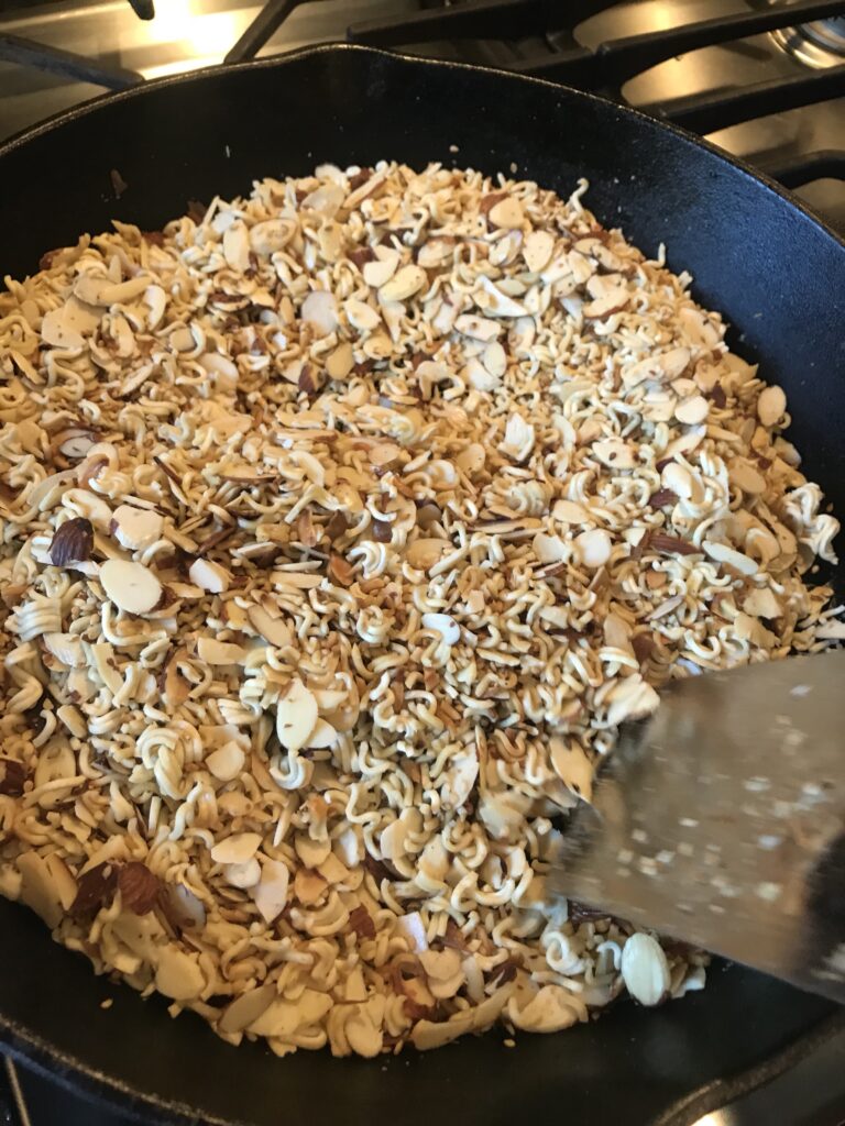 Noodles and almonds being stirred around the pan