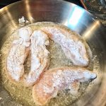 Chicken tenders cooking in a pan.
