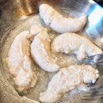 Chicken tenders cooking in a pan.