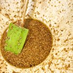 The marinade, with soy sauce and sesame seeds in a bowl with a green spatula.