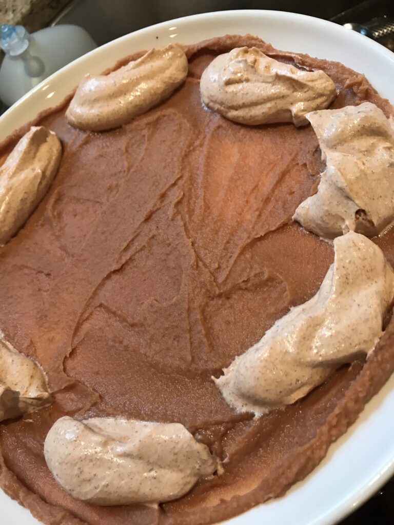 The sour cream being applied to the bean dip spread