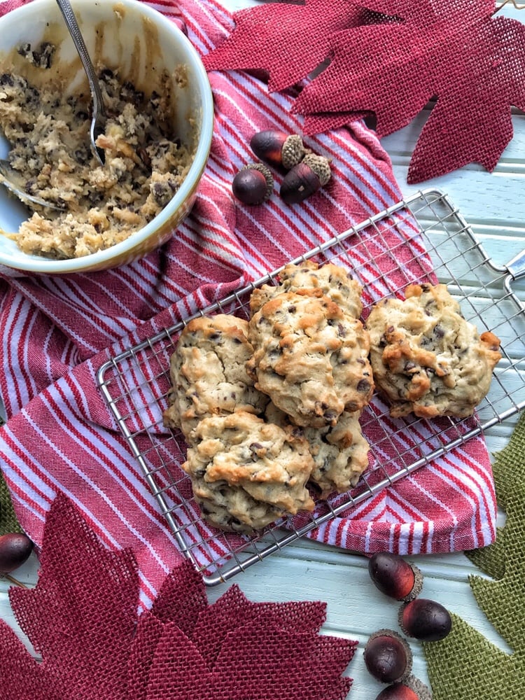 The cookie batter in a bowl next to the finished cookies on a metal tray surrounded by fall decorations.