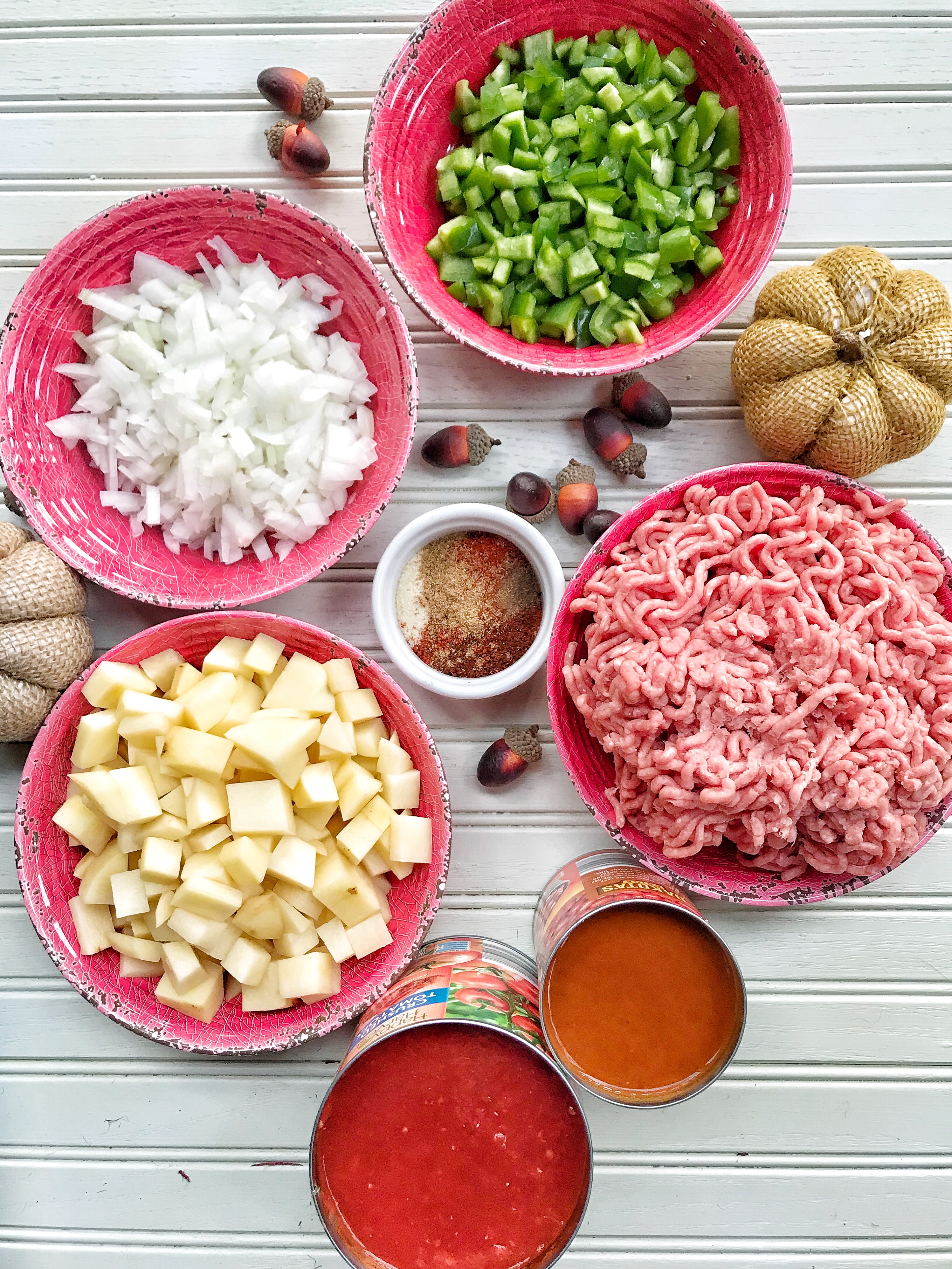 The ingredients for crockpot chili in various red bowls
