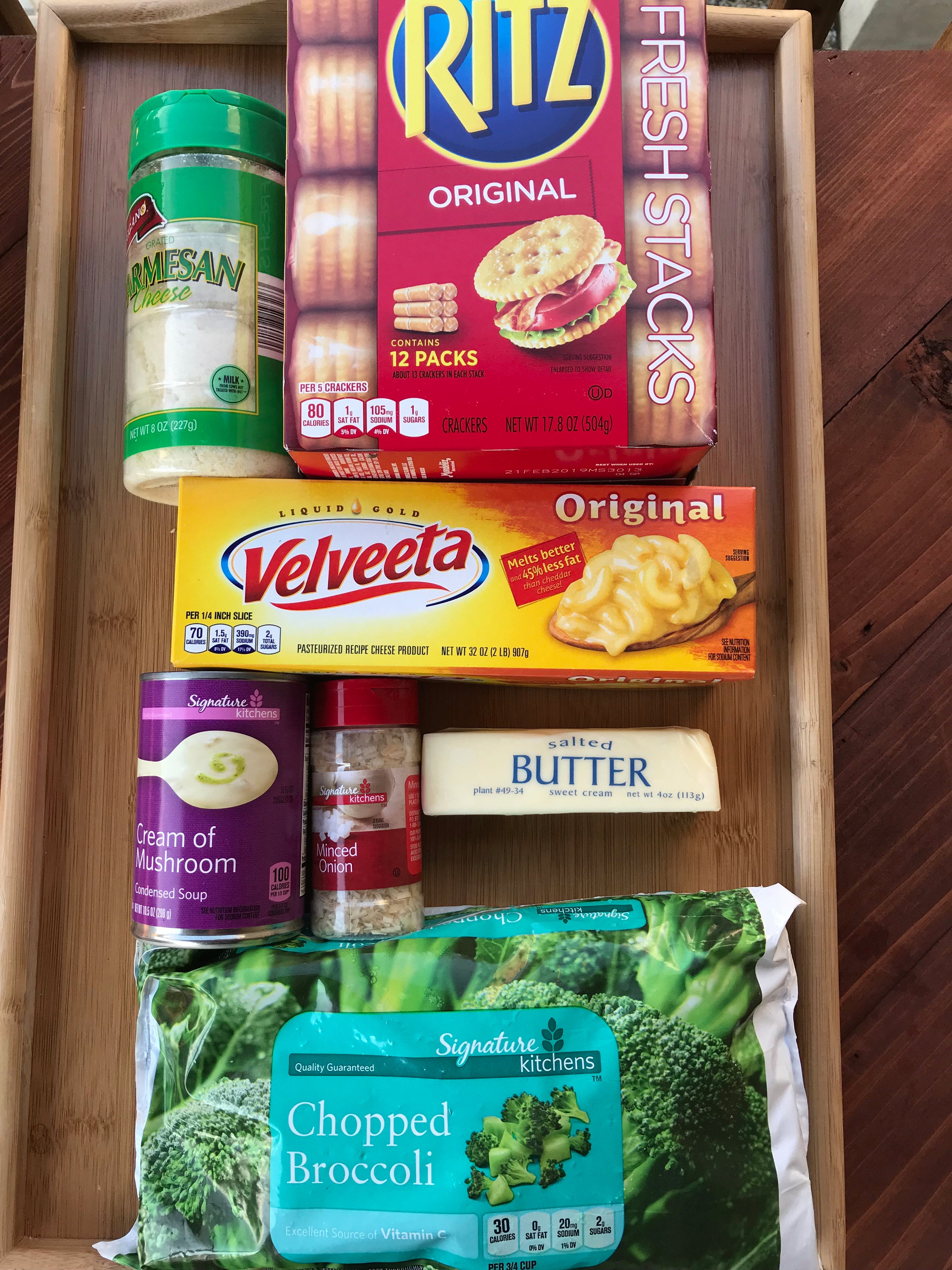 The ingredients for the casserole, including Parmesan Cheese, crackers, Velveeta, butter, cream of mushroom soup, minced onion, and chopped broccoli
