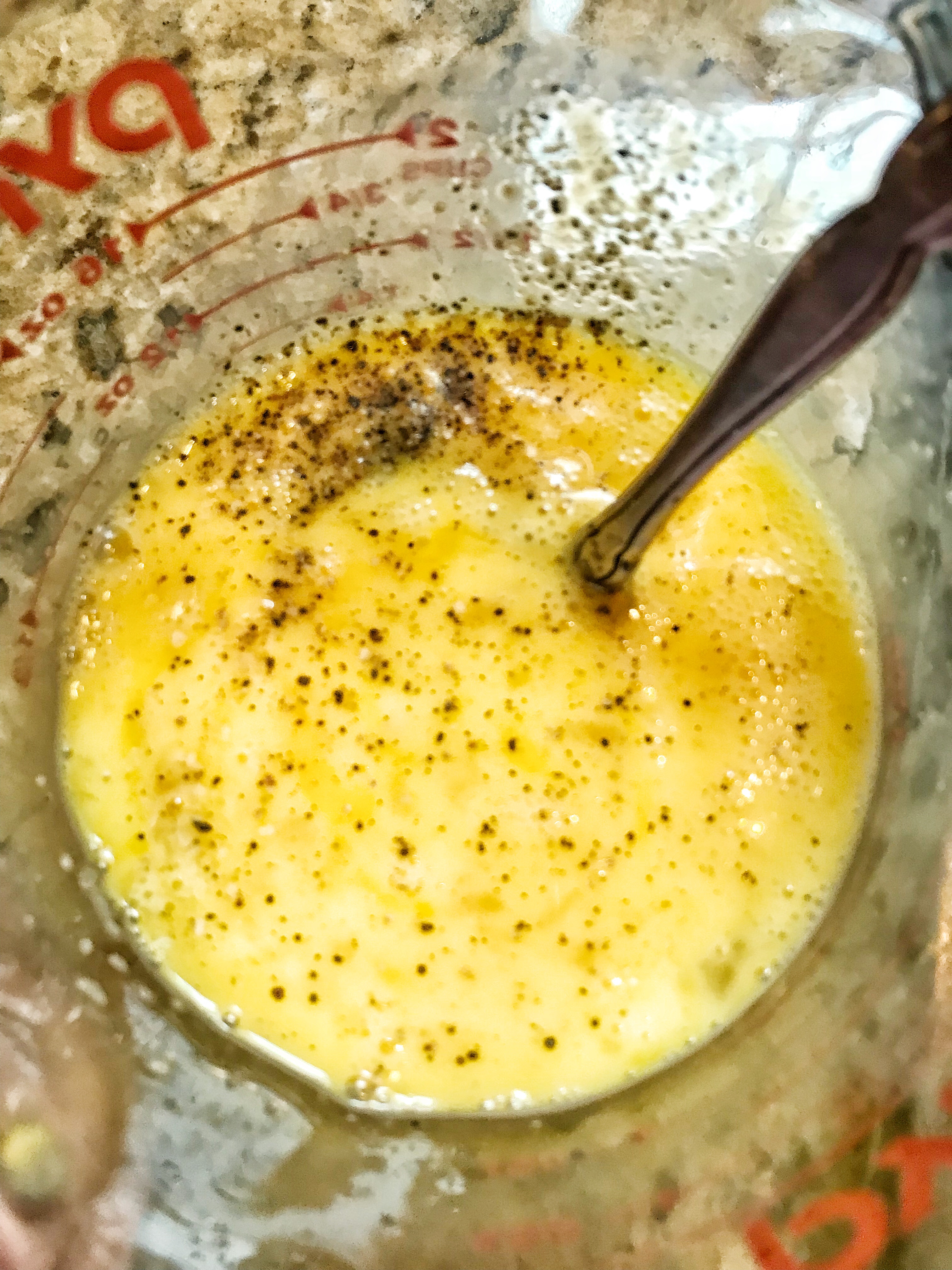 Egg, salt, and pepper in a Pyrex measuring cup