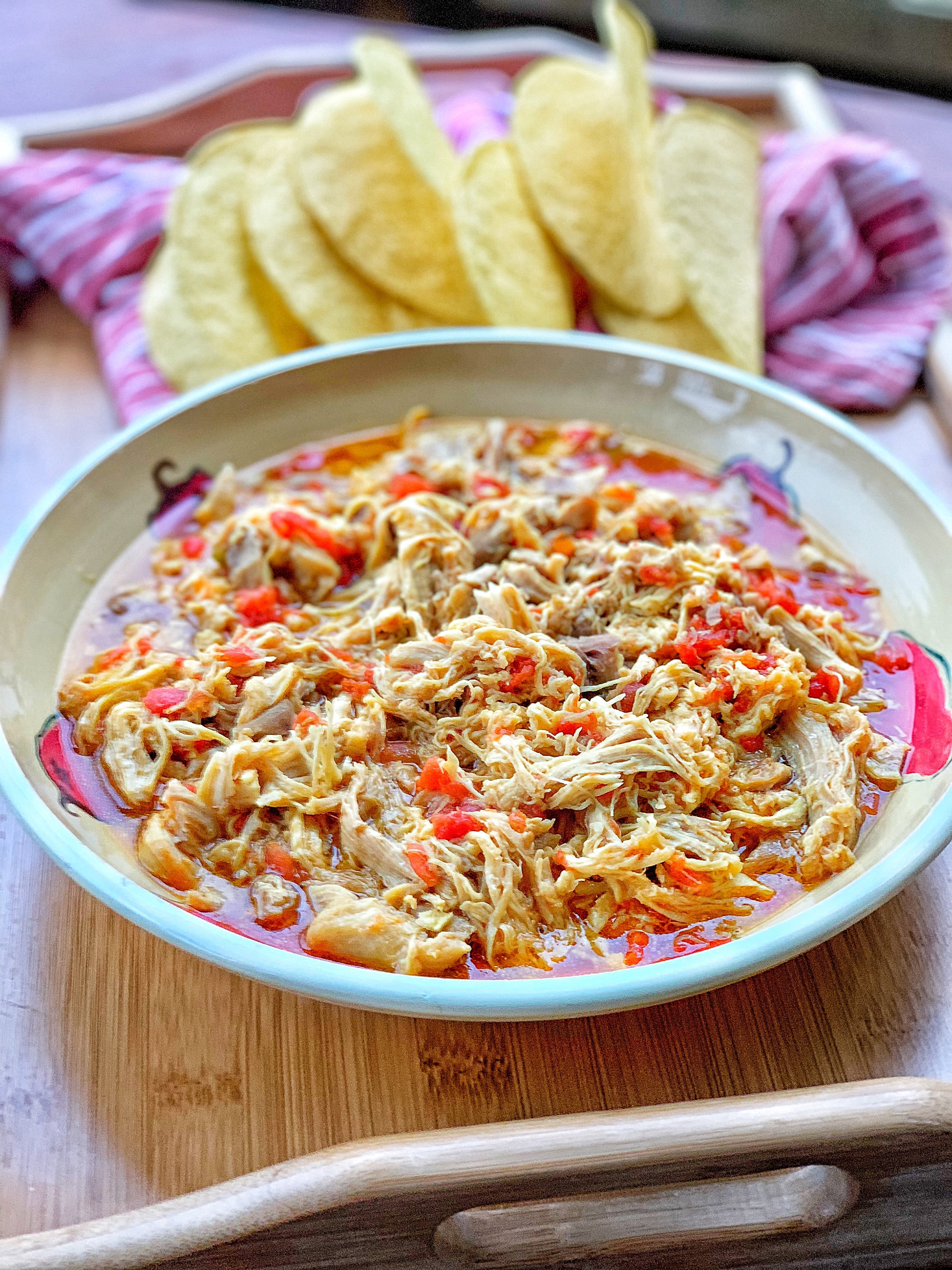 Shredded chicken taco meat in a dish in front of taco shells