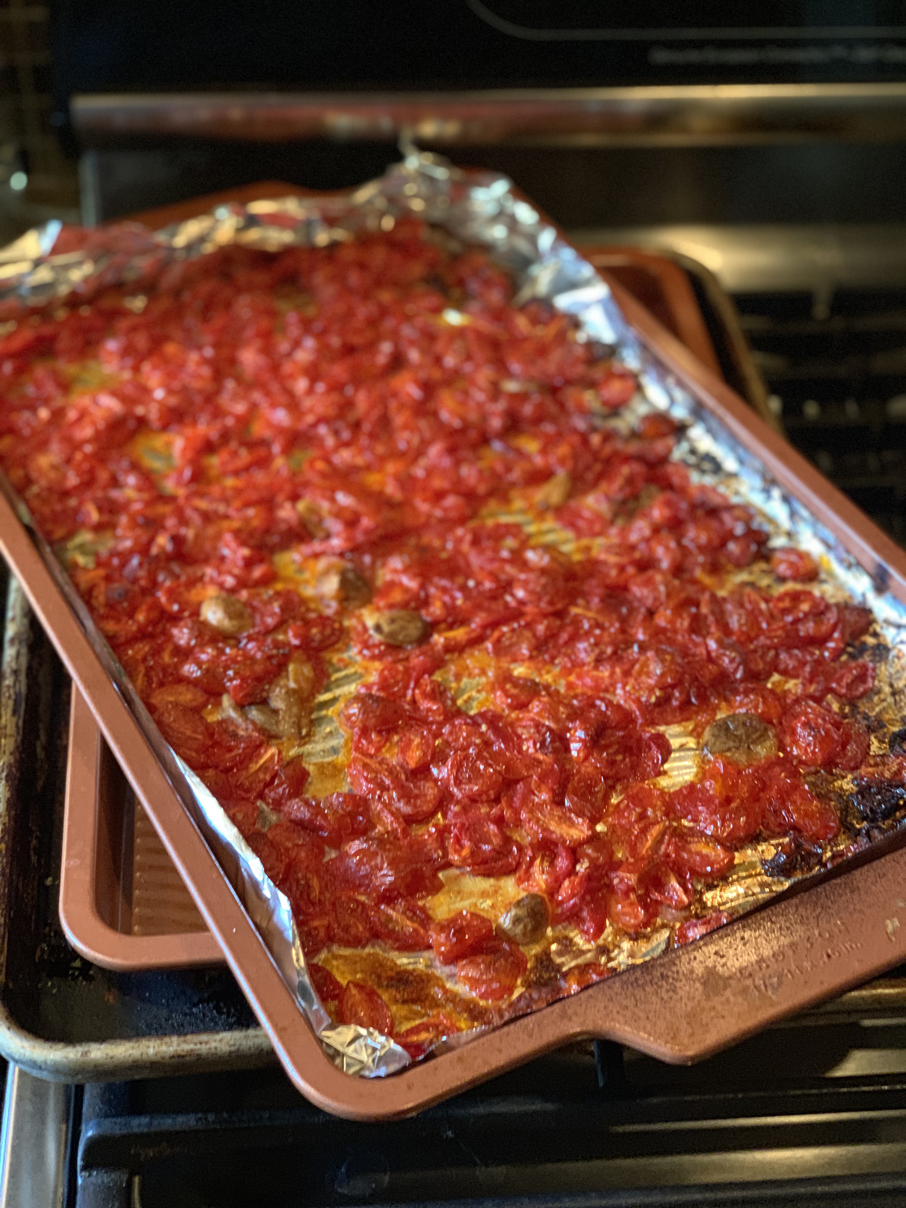 A sheet pan with tin foil with oven roasted tomatoes on it.