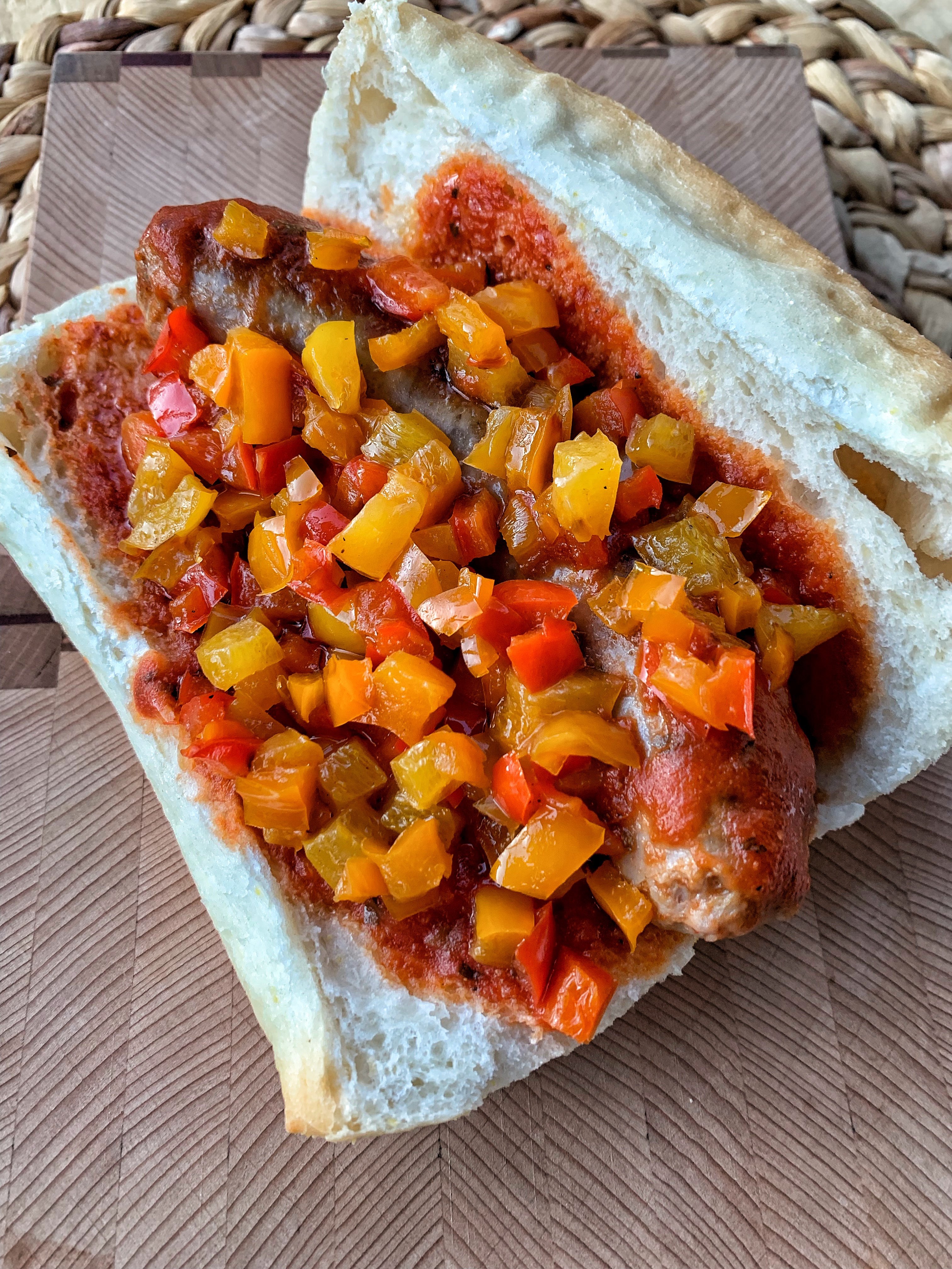 A picture of a sausage sandwich with tri colored peppers