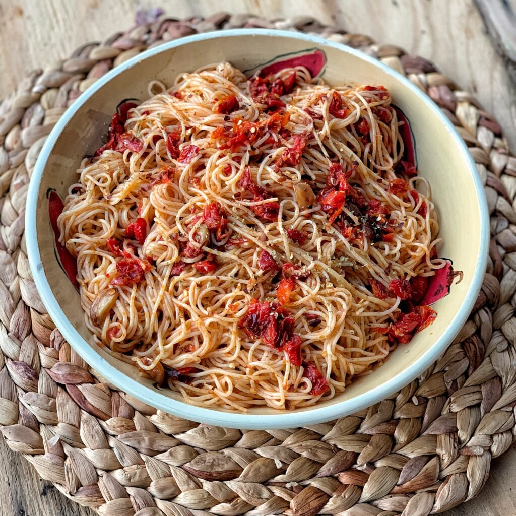 A bowl of pasta with tomatoes and olive oil.
