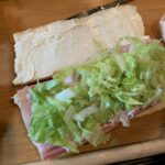 Shredded lettuce on ham on French bread sandwich