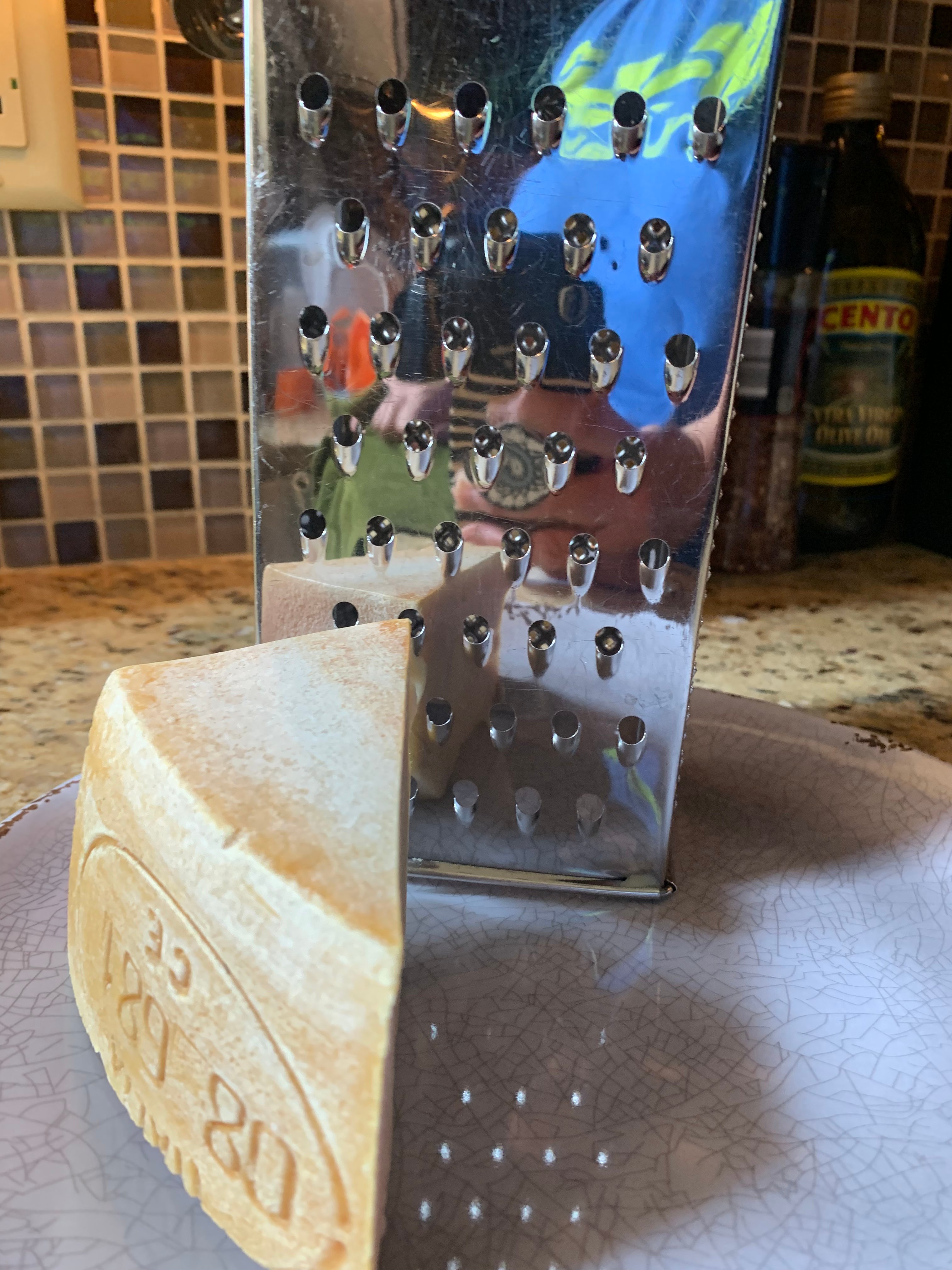 A block of parmesan cheese next to a cheese grater