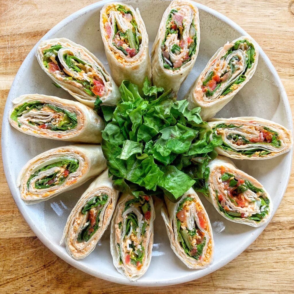 A plate with 12 tortilla pinwheel sandwiches.