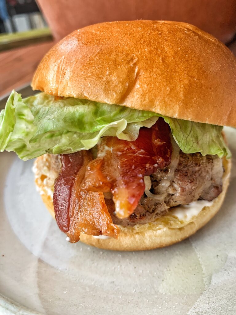 One cheese burger with a brioche bun, bacon and crisp lettuce.