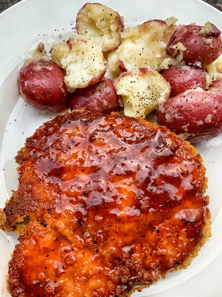 Pork chop with bbq sauce on top and red potatoes with butter