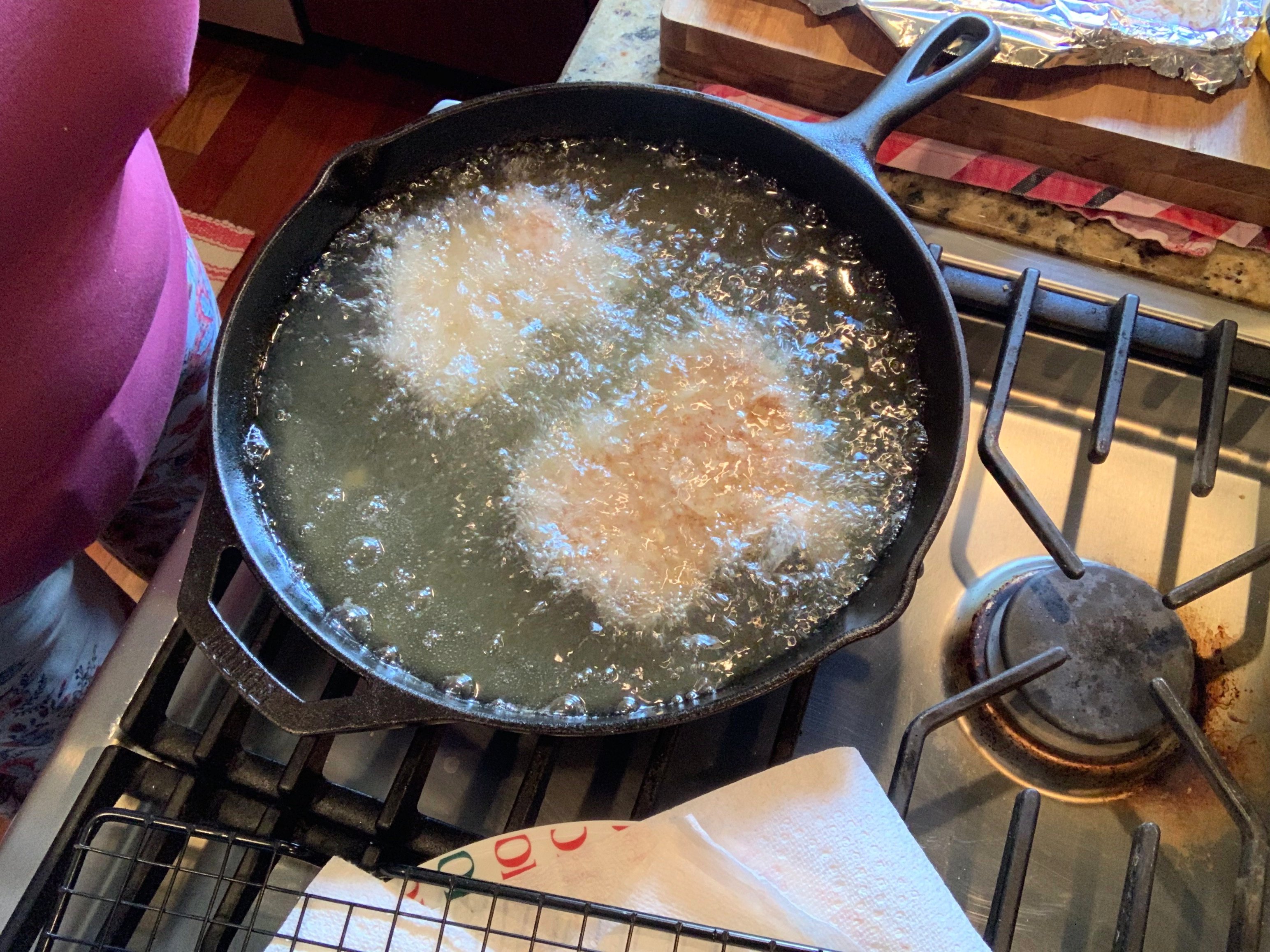 Two pieces of chicken frying in a skillet