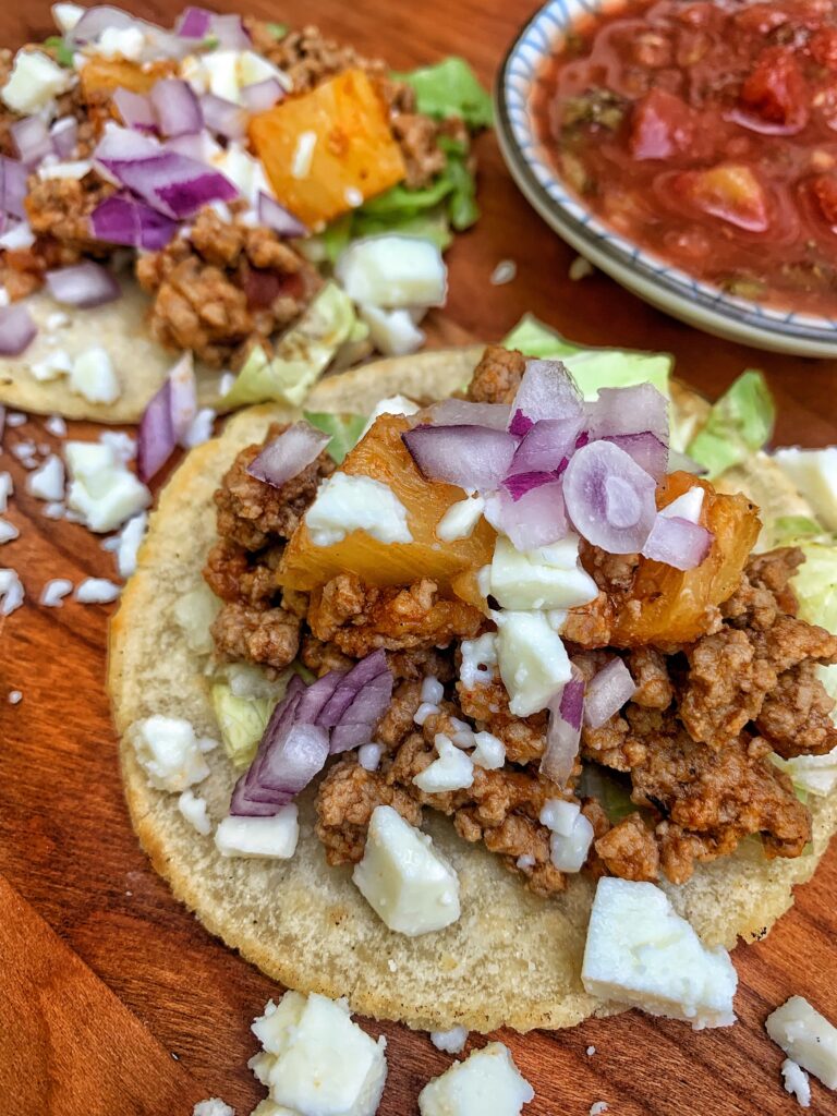An Al Pastor taco with various toppings