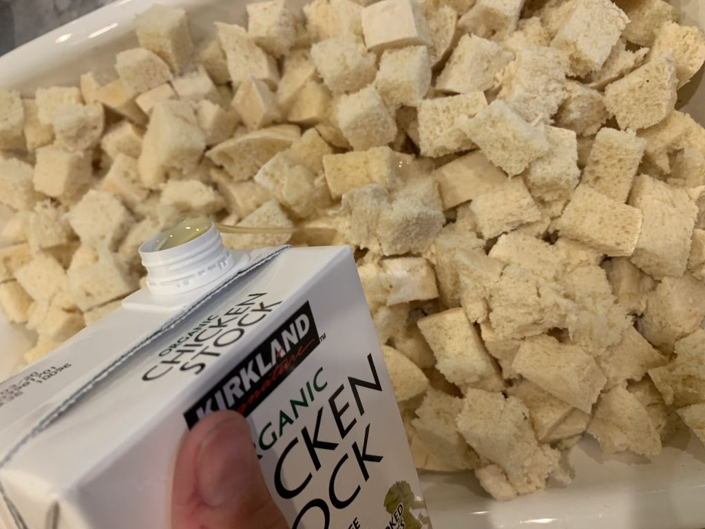 Chicken stock being poured into cubed bread dumplings