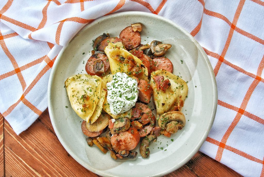 Polish sausage stir fry with pierogi, mushrooms, and onions topped with sour cream
