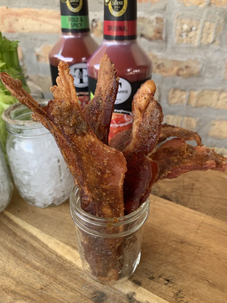 A glass cup with candied bacon in it