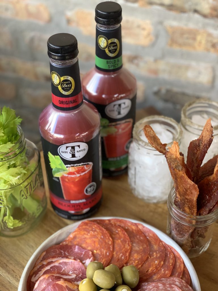 The Bloody Mary bar, with two bottles of Bloody Mary mix, candied bacon, meats, and olives