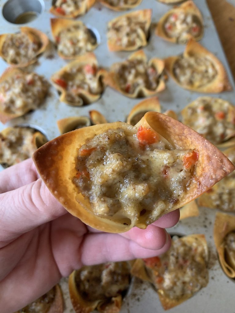 A close up of a baked wonton wrapper with crumbled sausage and creamy cheese