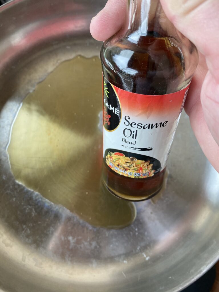 A bottle of sesame oil over a skillet