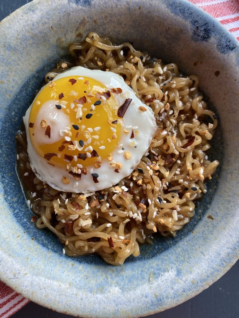 Ramen in a bowl topped with seasonings and an egg