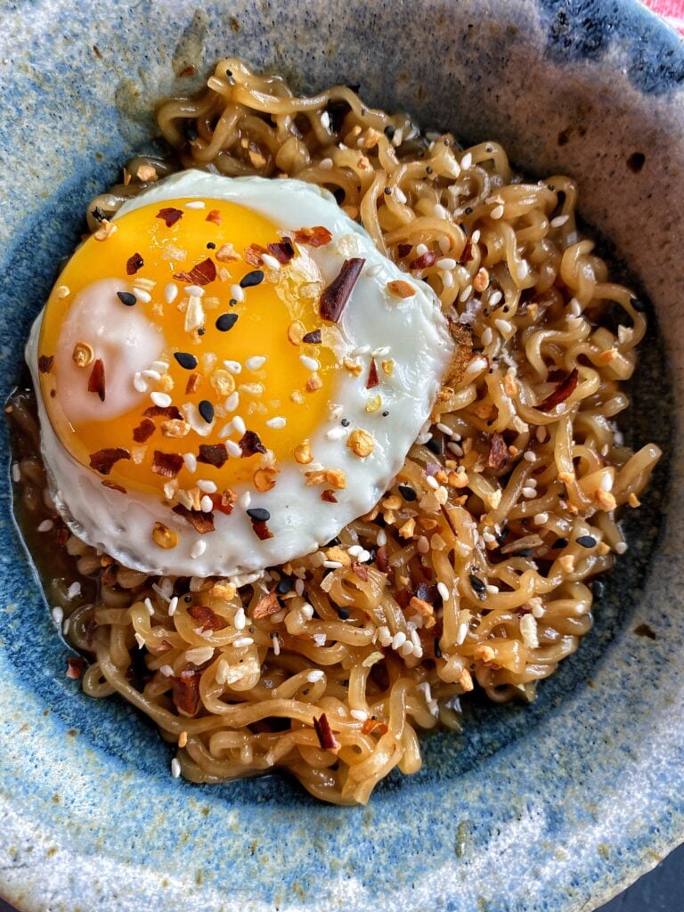 Ramen in a bowl topped with seasonings and an egg