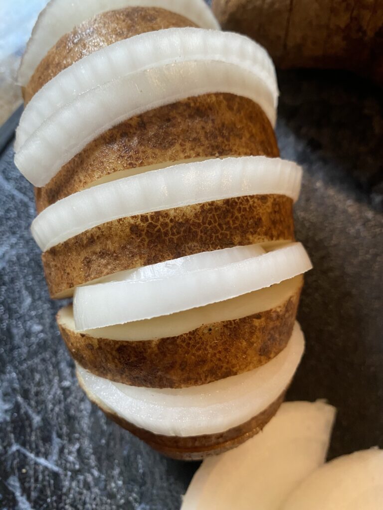 Onion slices placed in between the slots cut into the potato