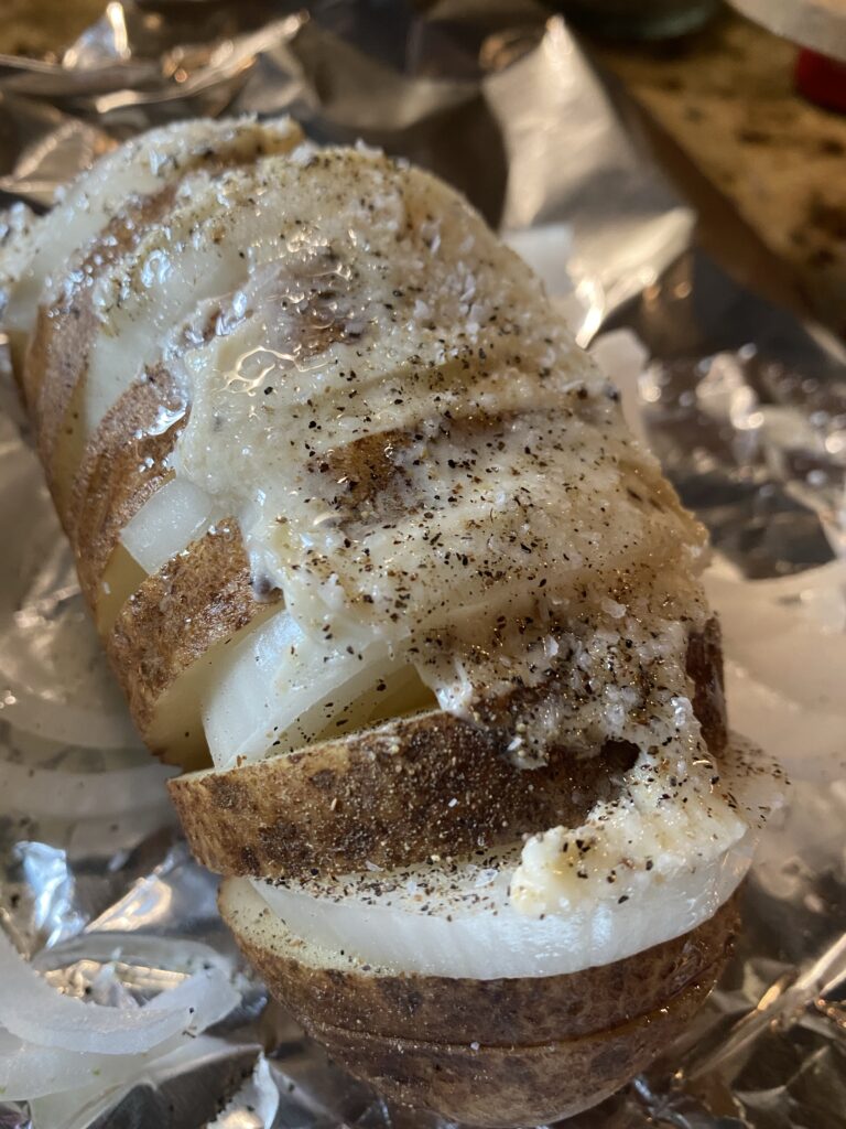 Butter and seasoning on top of the Hasselback Potato before baking