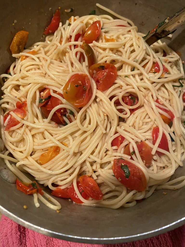Pasta and grape tomato mixture being mixed in a pot